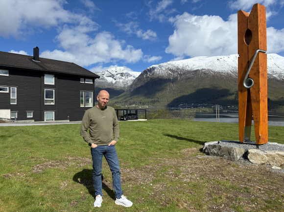 Tomas Ryste framfor verdas største klesklype, som han har sett opp like utanfor huset sitt. Han vonar klypa får plass i Guinness World of Records. Foto: Bent Tandstad / NPK